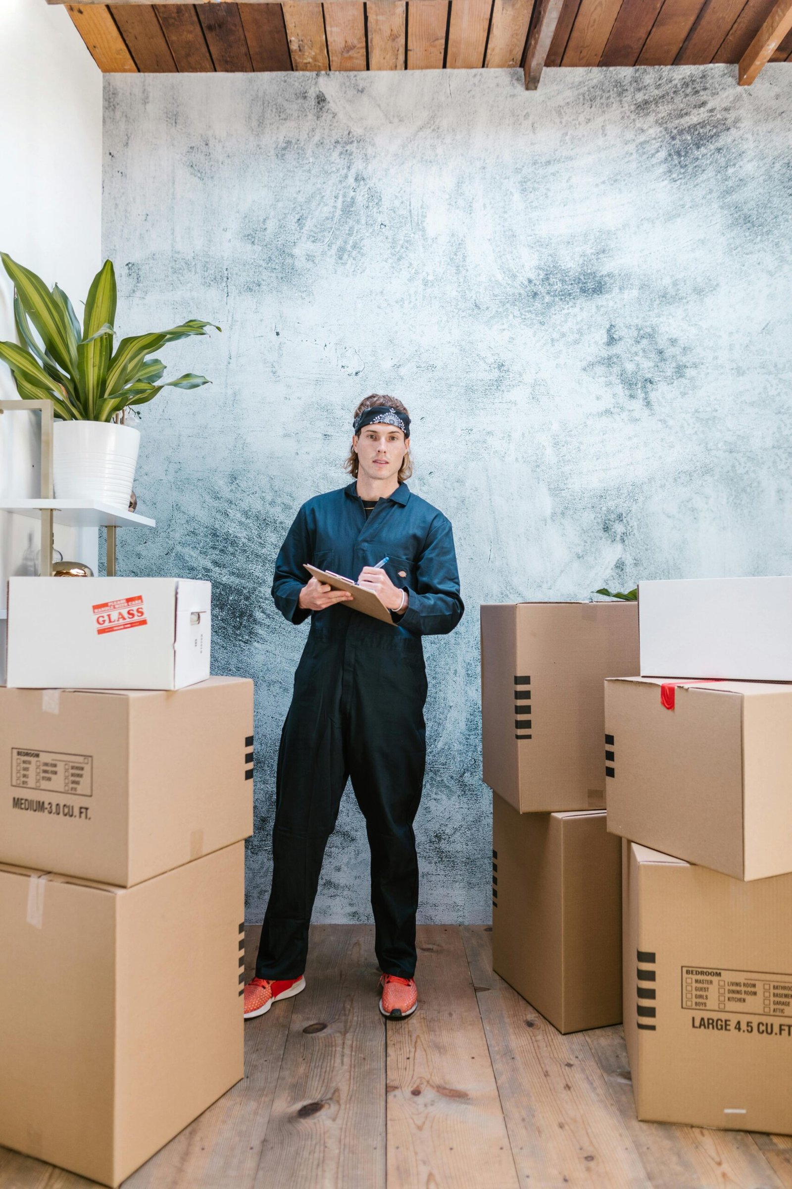 Professional mover in coveralls organizing packages for moving day.